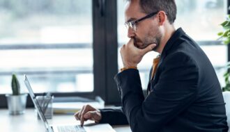 Handsome mature entrepreneur working with computer in real estate.