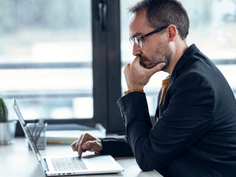 Handsome mature entrepreneur working with computer in real estate.